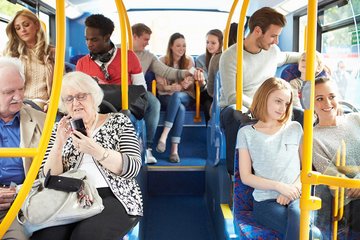 Menschen verschiedenen alters sitzen in einem Bus. Ansicht von innen, Mittelgang nach hinten.