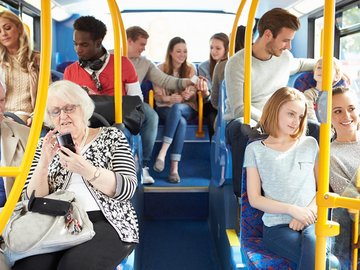 Menschen verschiedenen alters sitzen in einem Bus. Ansicht von innen, Mittelgang nach hinten.