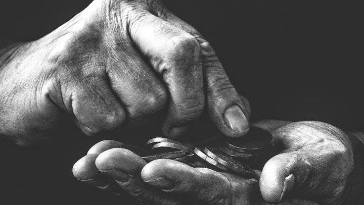 Das Bild in schwarz-weiß zeigt zwei Hände mit Kleingeld.
